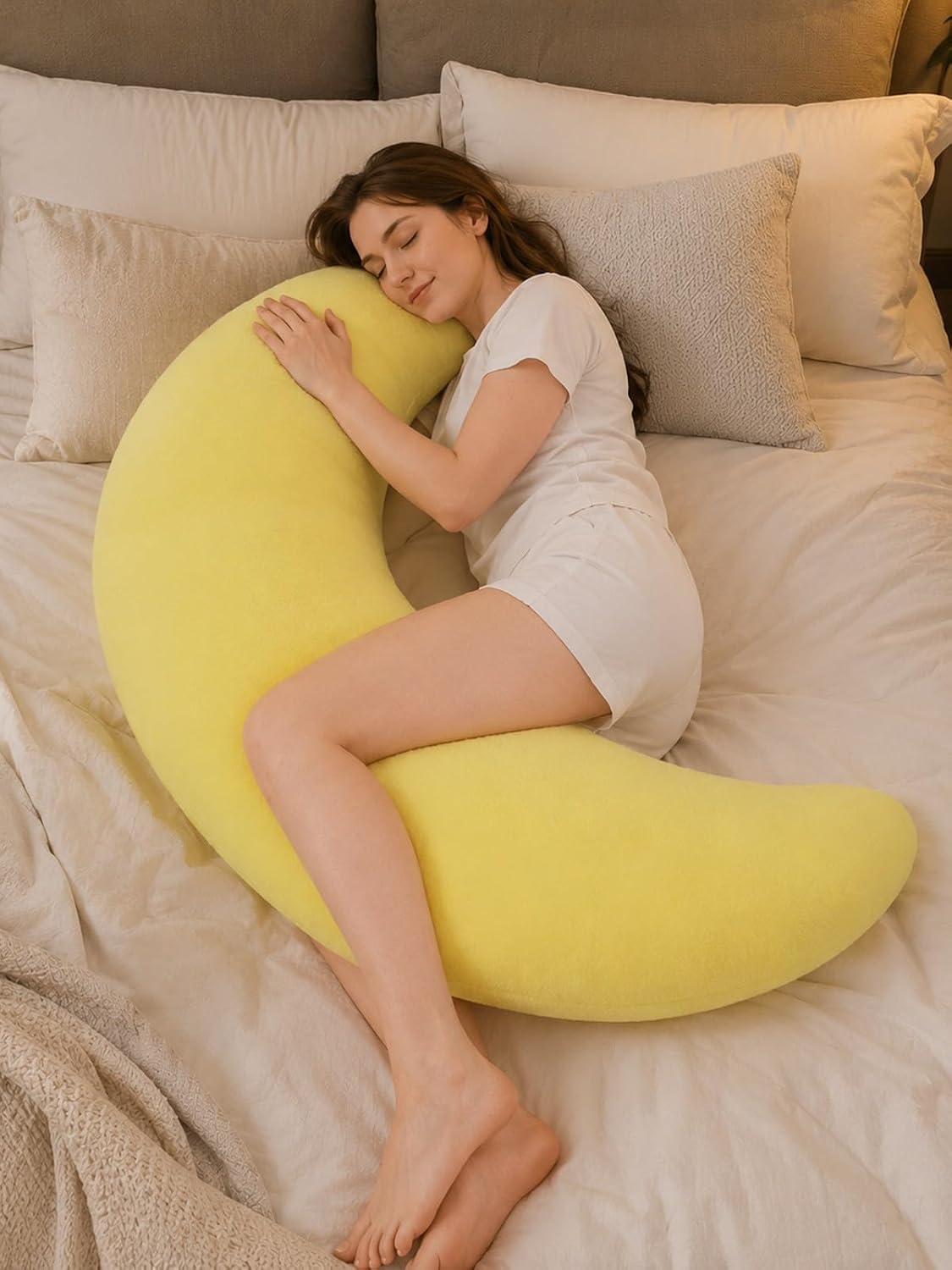 Woman hugging the yellow crescent moon body pillow on a bed