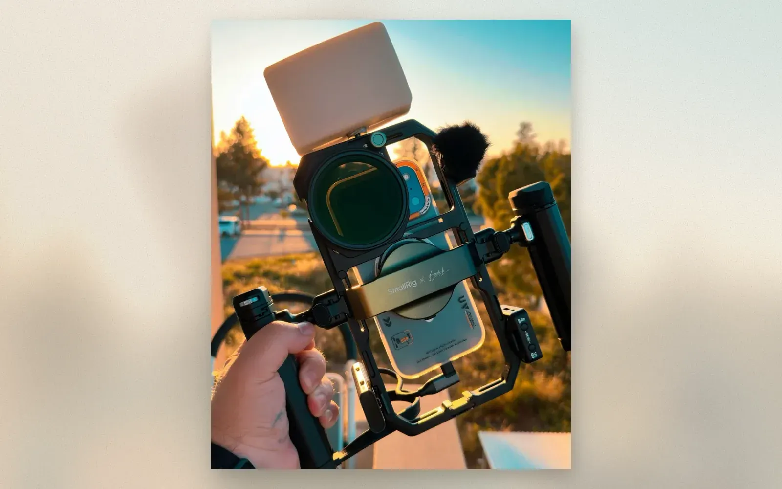 SmallRig x Brandon Li mobile video rig held in hand with phone, ND filter, wireless mic, and LED panel at sunset