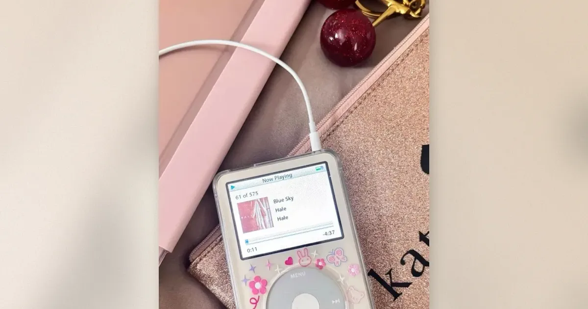 Weißer refurbished iPod Classic im transparenten Case mit Kawaii-Hasen- und Blumenstickern, Now-Playing-Bildschirm zeigt einen Titel