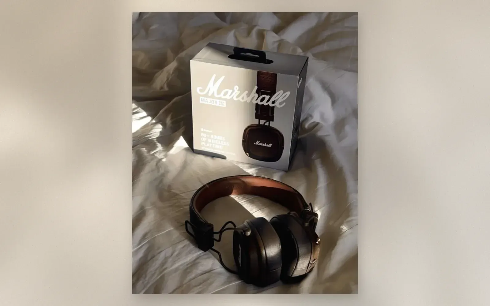 Marshall Major IV on-ear headphones in brown lying next to their box on white bedsheets