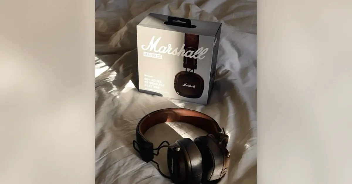 Marshall Major IV On-Ear-Kopfhörer in Braun neben der Verpackung auf weißer Bettwäsche