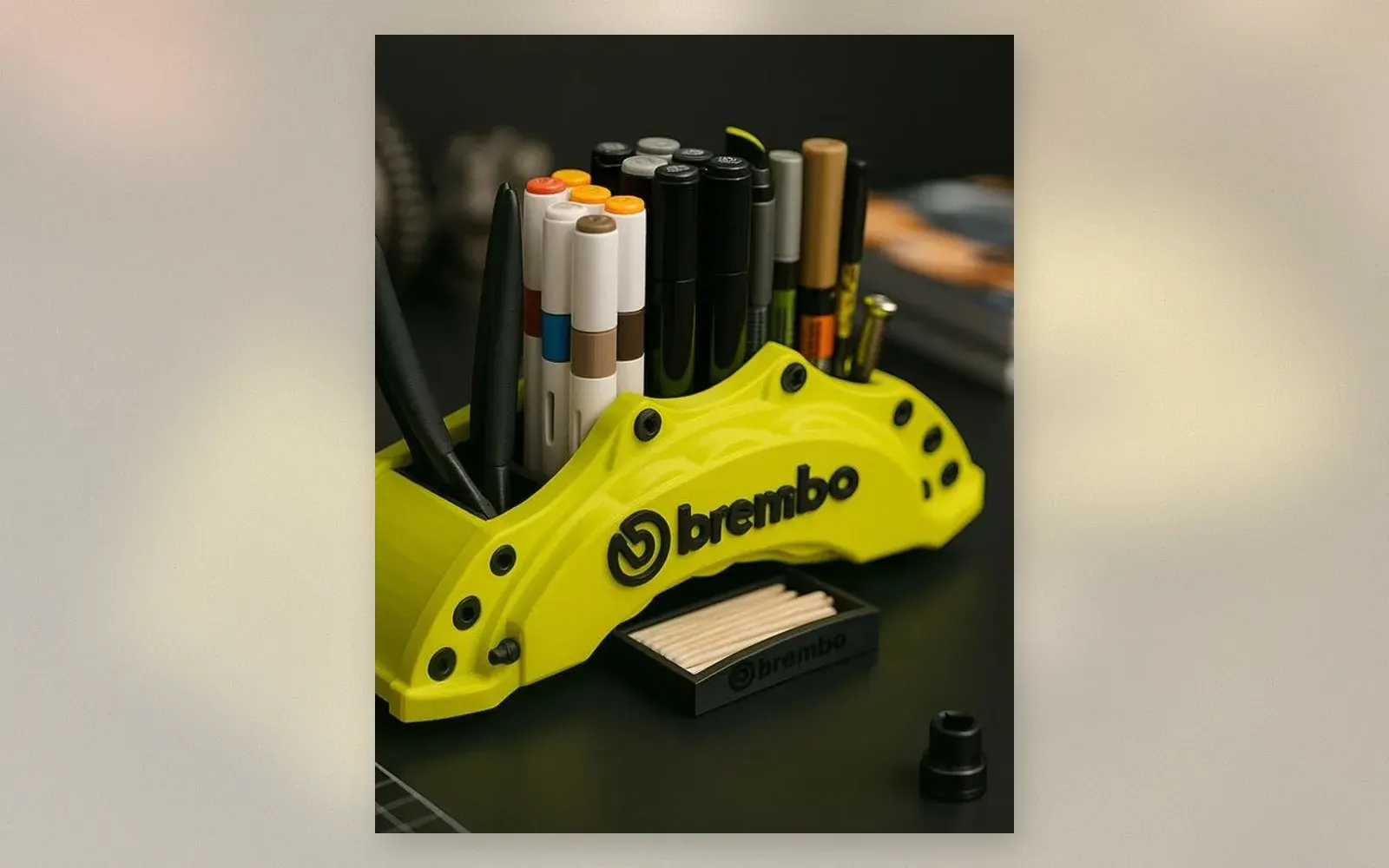 Lime green Brembo brake caliper pen holder with markers and tools on a dark desk