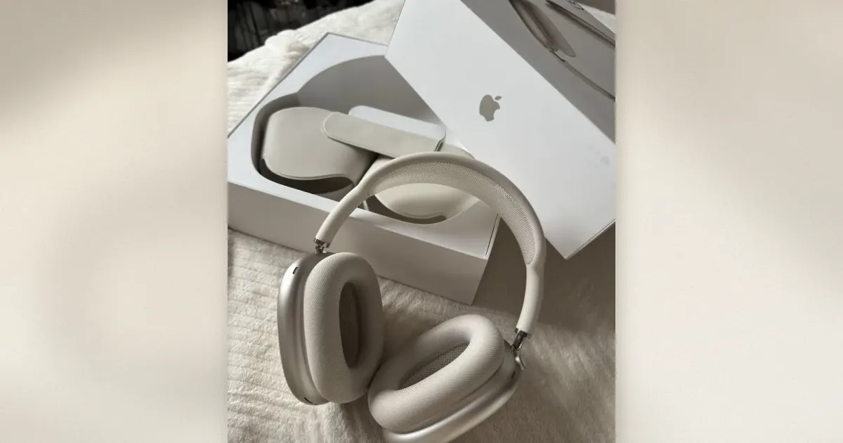 Apple AirPods Max Kopfhörer in Sternenlicht auf einer weichen Decke neben der geöffneten Verpackung