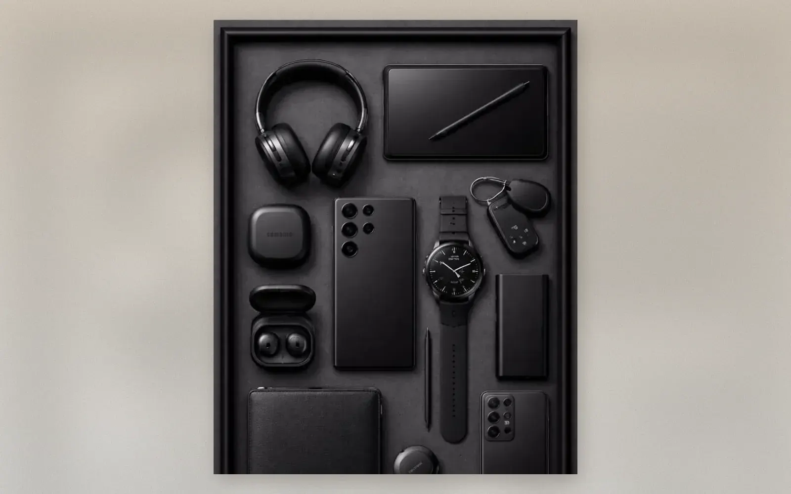 Samsung Galaxy ecosystem flat lay in all black: watch, tablet, phone, buds, SmartTag trackers, charger, and wallet
