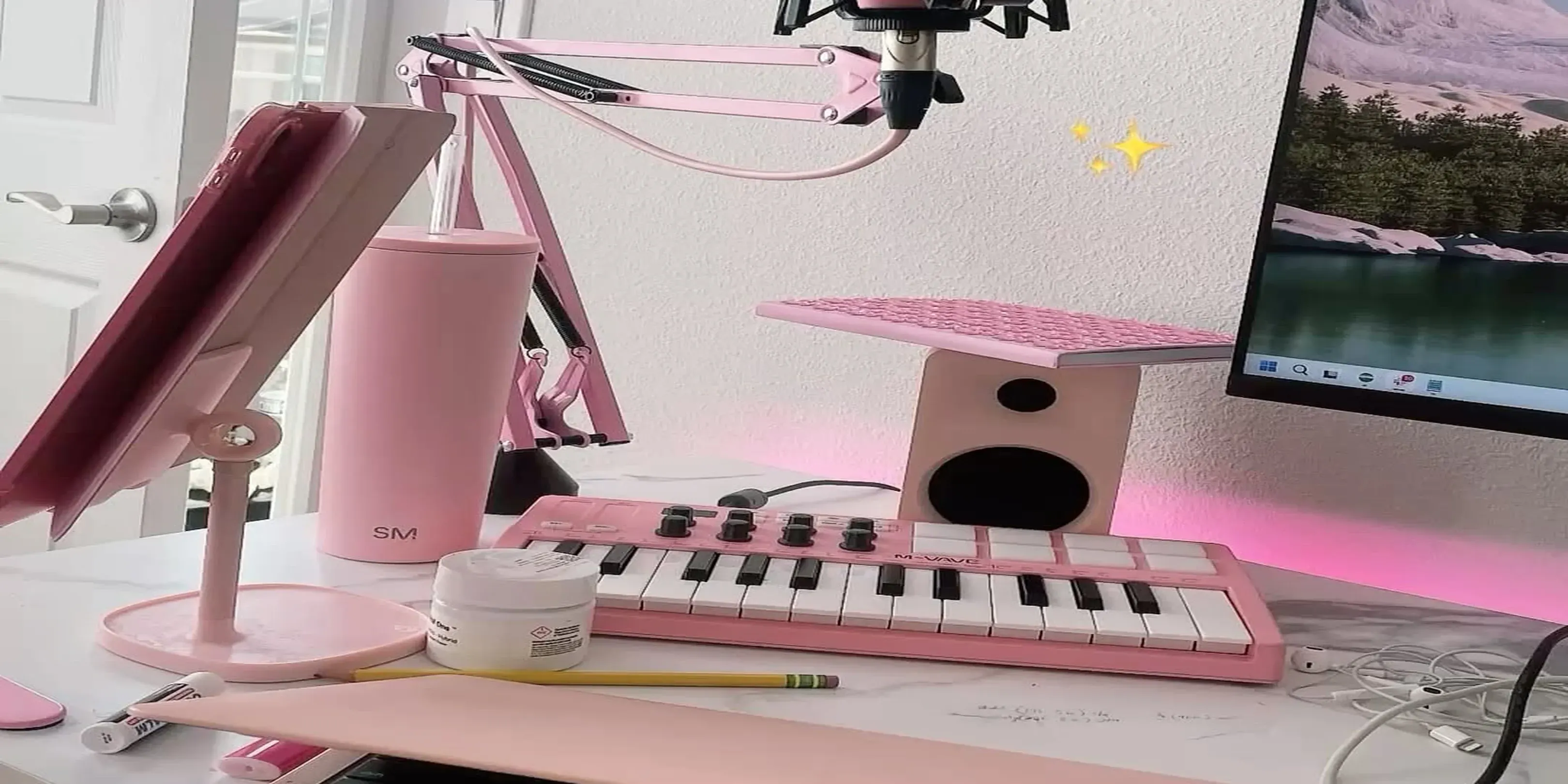 Pink desk setup with a condenser microphone in a shock mount on a pink boom arm, a pop filter, a small pink M-VAVE MIDI keyboard and pink LED backlighting