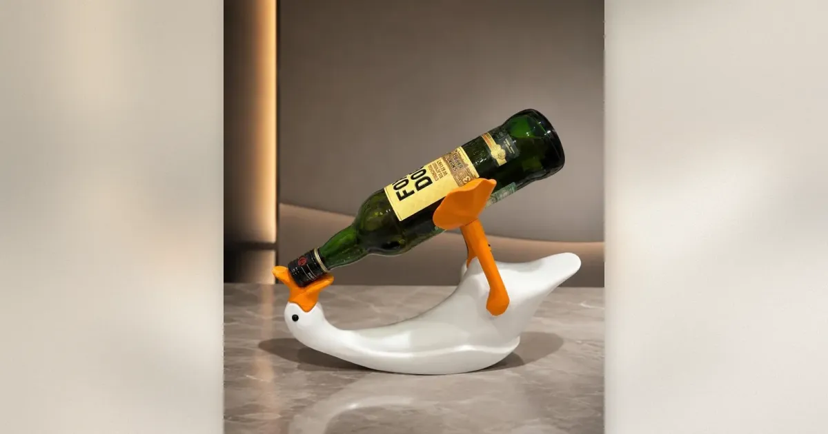 Weiße keramische Ente-Weinflaschenhalter mit orangem Schnabel, die eine grüne Weinflasche hält