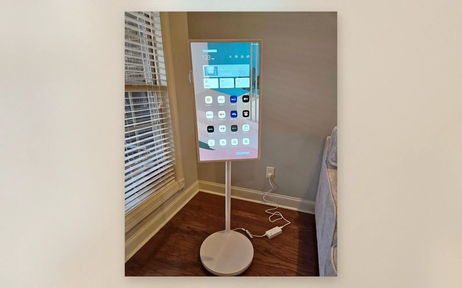 Smart TV standing in portrait mode next to a bright window with streaming apps on screen