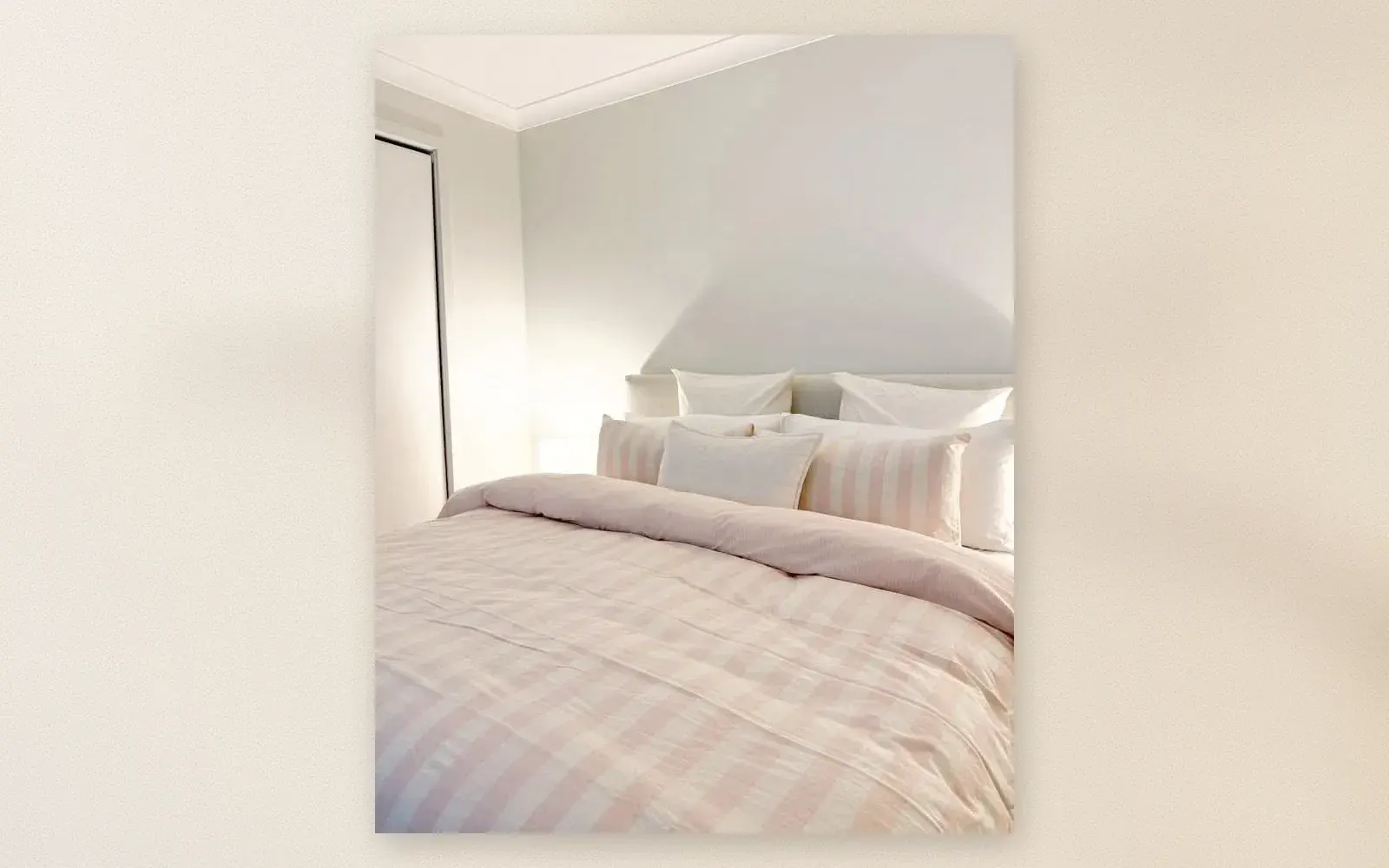 A bed dressed in a pink and white checked gingham duvet cover with striped pillowcases