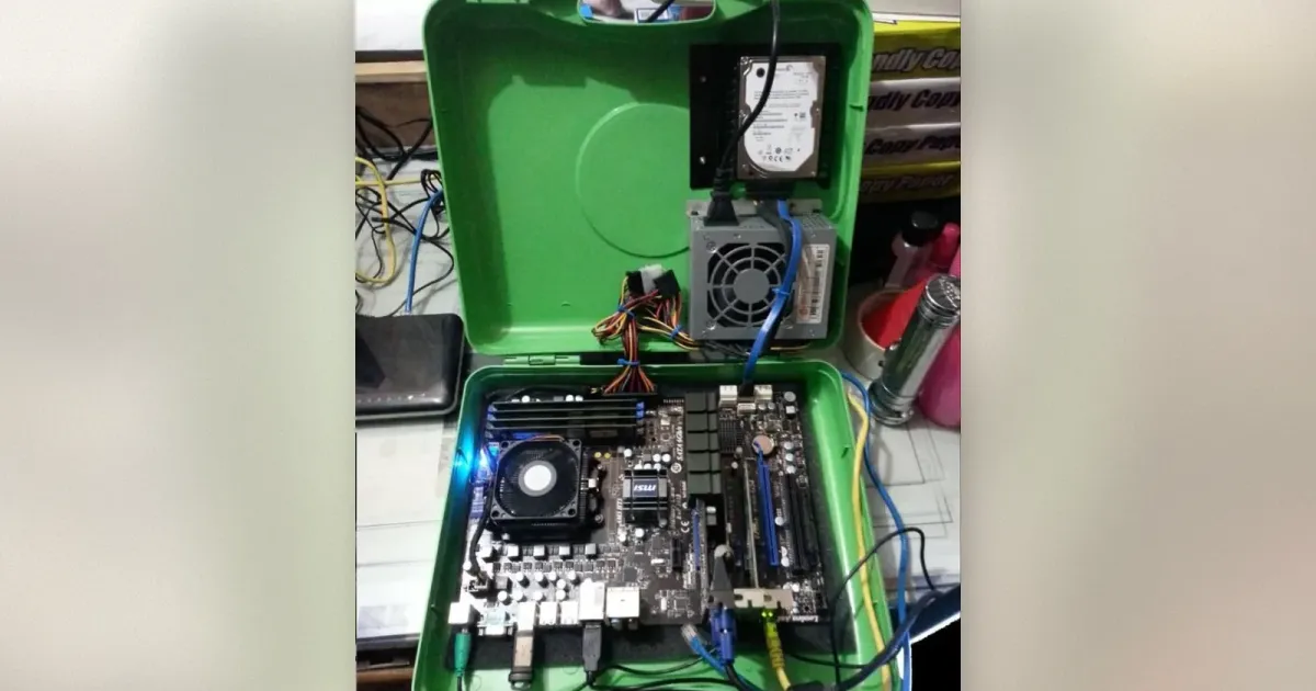 Grüner Werkzeugkoffer geöffnet mit MSI-Mainboard, CPU-Kühler, RAM, Netzteil und Festplatte montiert