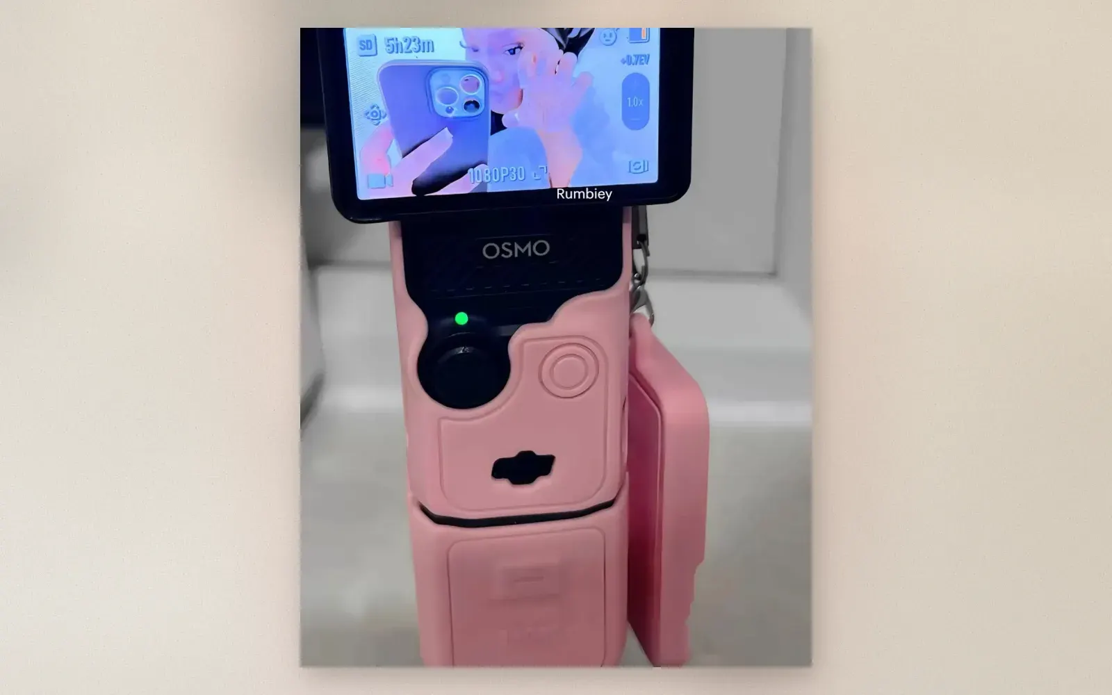 DJI Osmo Pocket 3 in a pink silicone protective case mounted on a mini tripod
