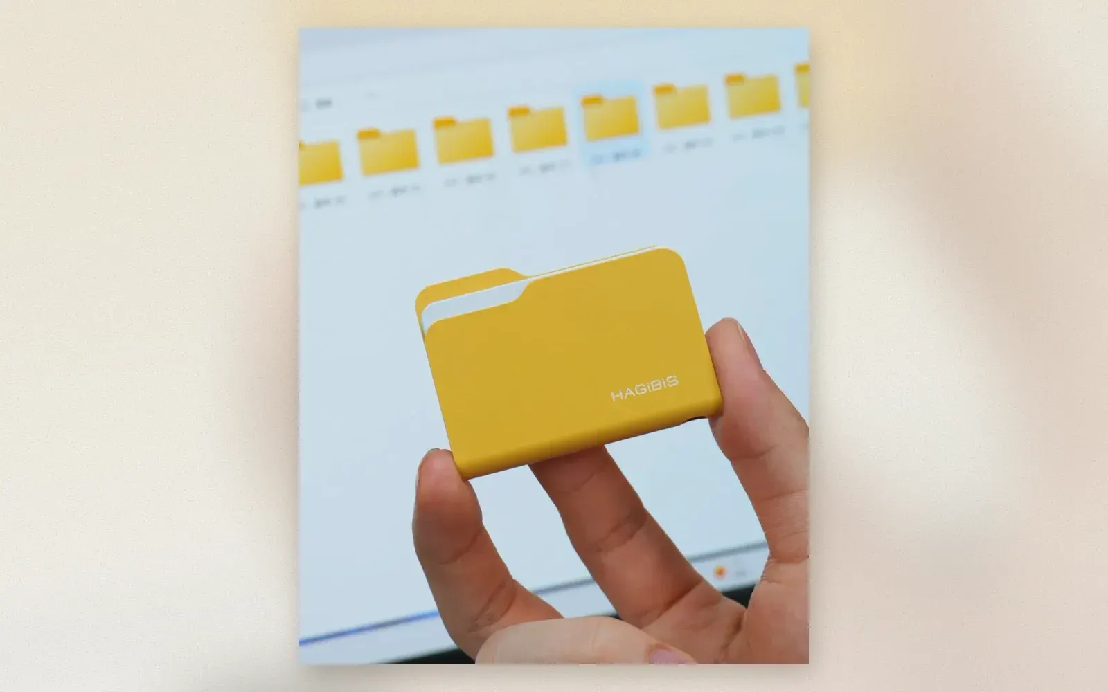 Yellow Hagibis folder-style NVMe SSD enclosure with a white paper accent, styled like a desktop folder icon