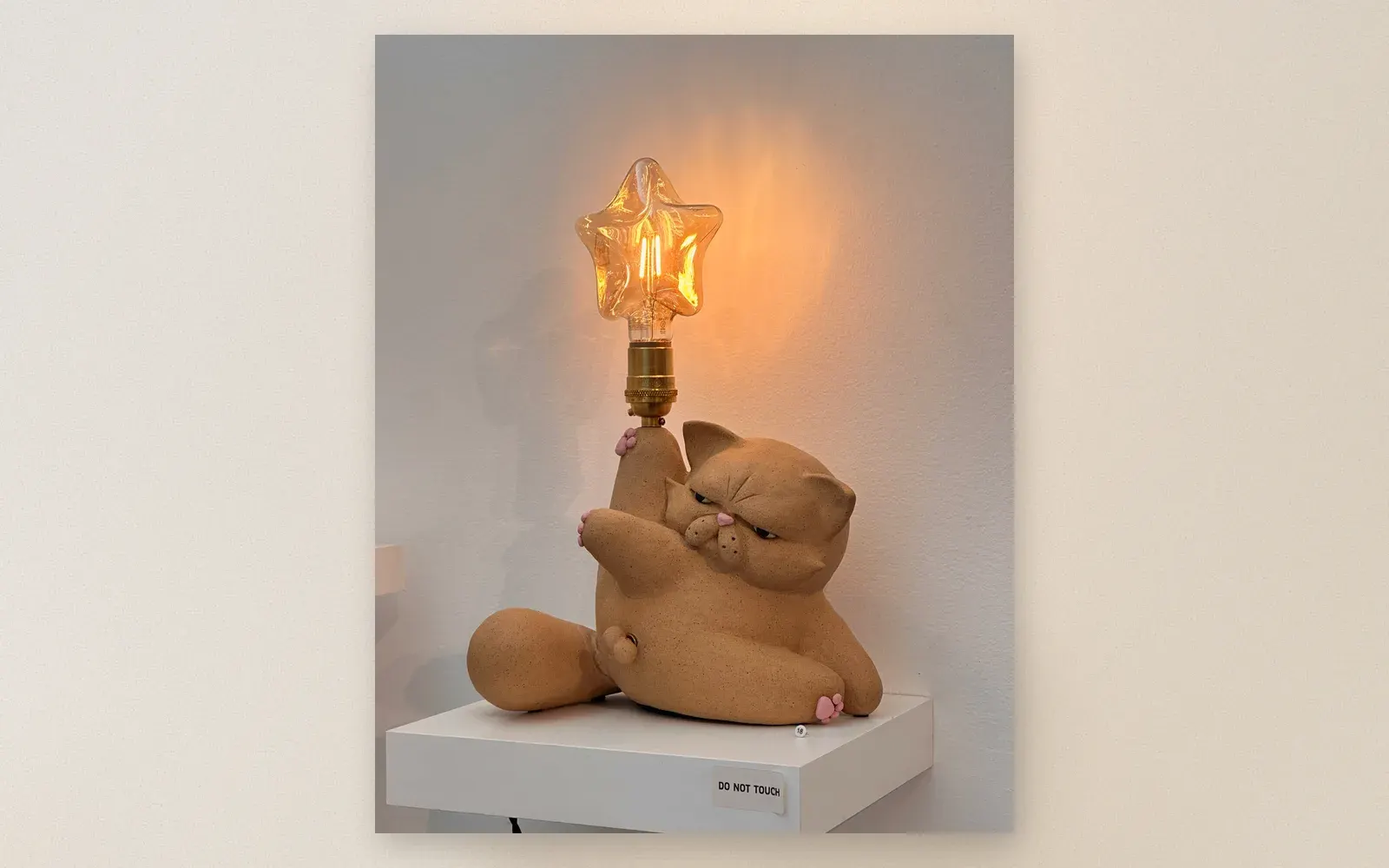 Ceramic cat lamp — grumpy cat figurine holding star-shaped Edison bulb