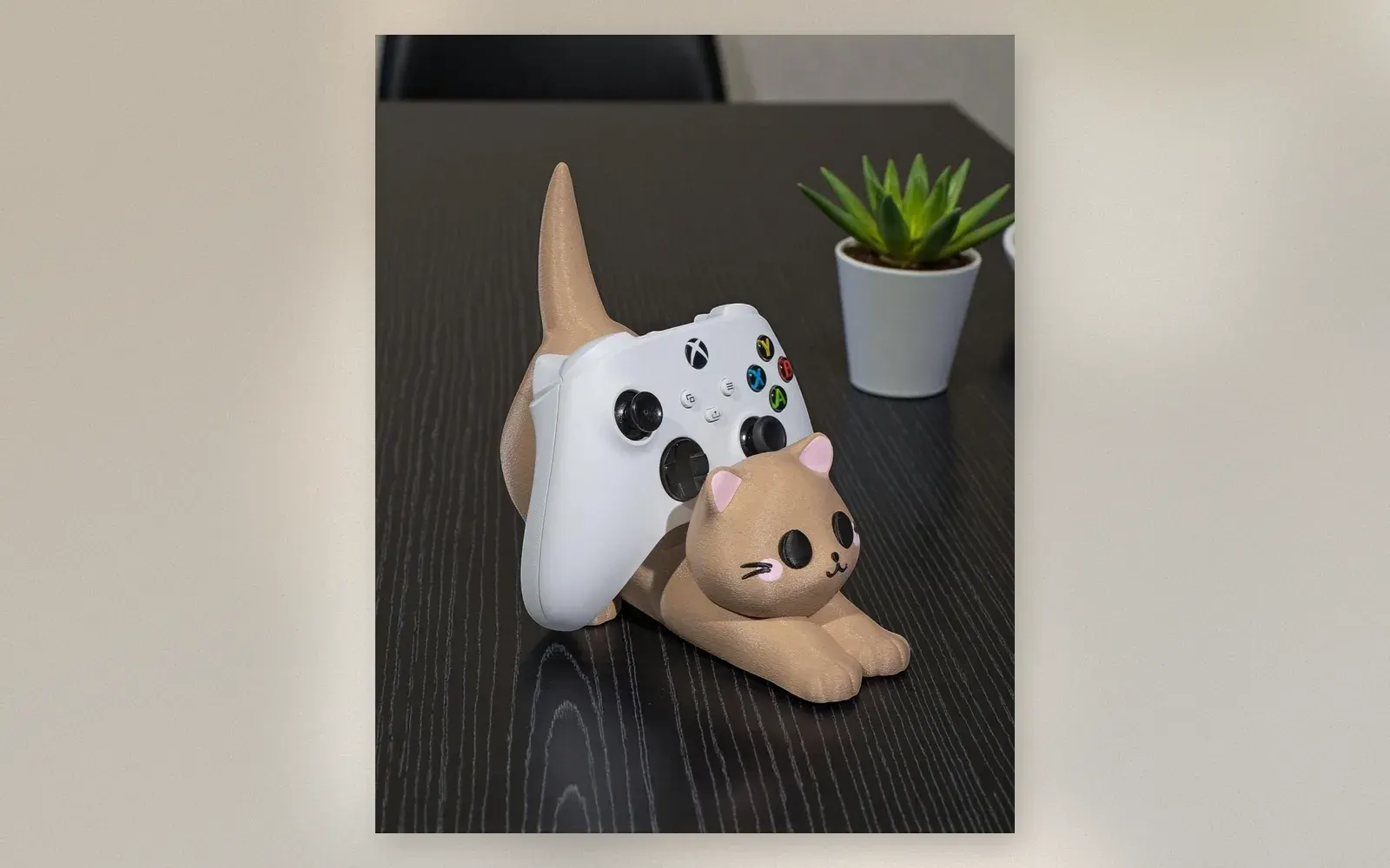 Cat game controller stand holding Xbox controller on its arched back