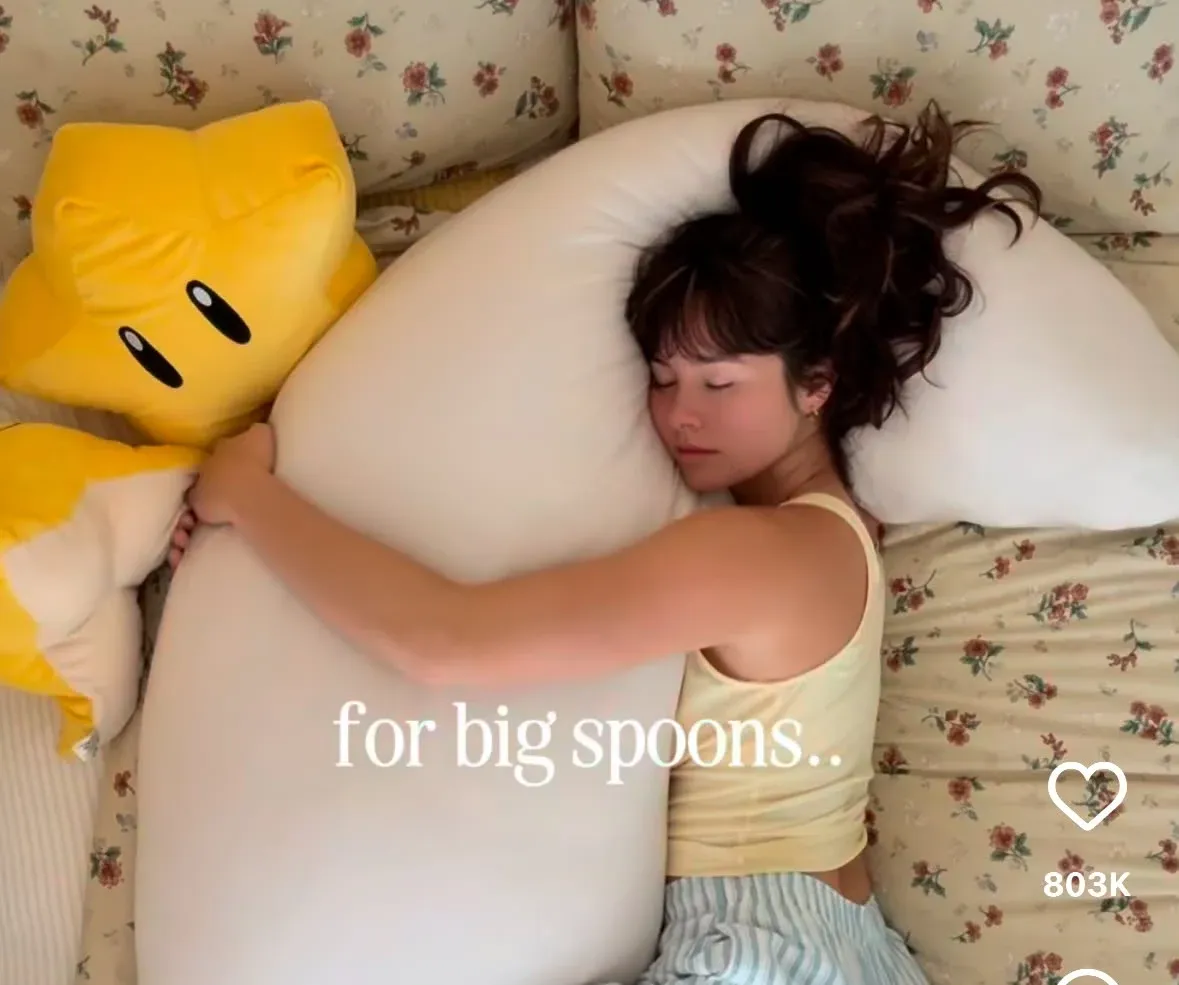 TikTok still of a side sleeper napping inside the crescent moon pillow