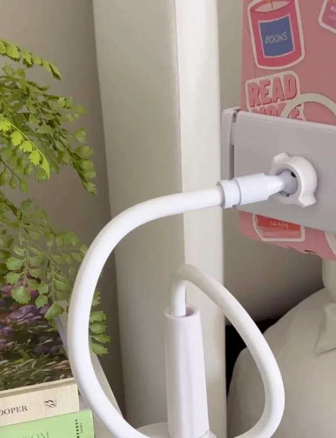 Spring cradle of a white gooseneck holder gripping a pink sticker-covered tablet