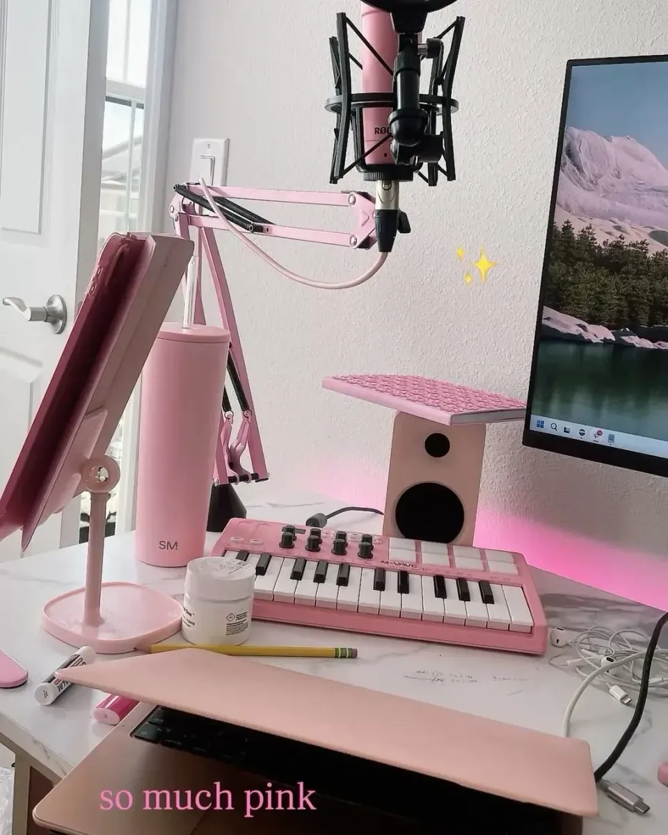 Close-up of the small pink 25 key MIDI keyboard with knobs and drum pads on the desk