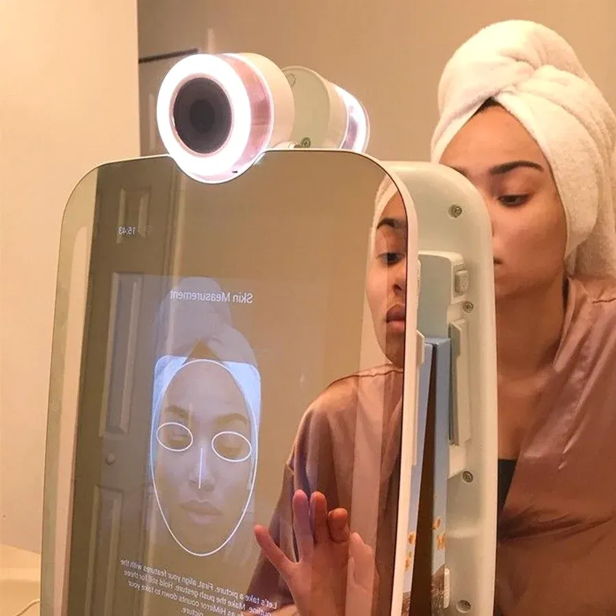 Woman with a towel turban using the HiMirror Slide in a bathroom while the skin measurement screen runs