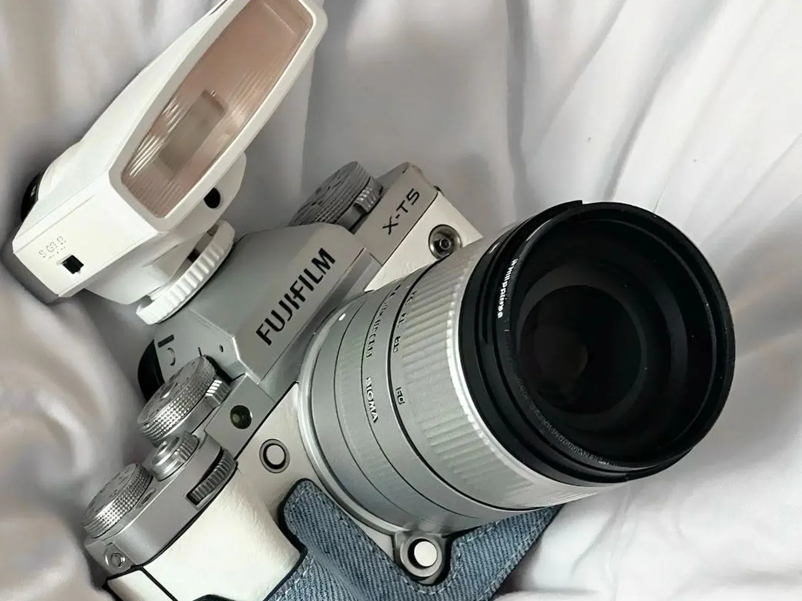 Close-up of the X-T5 top dials, white flash unit and silver Sigma lens barrel