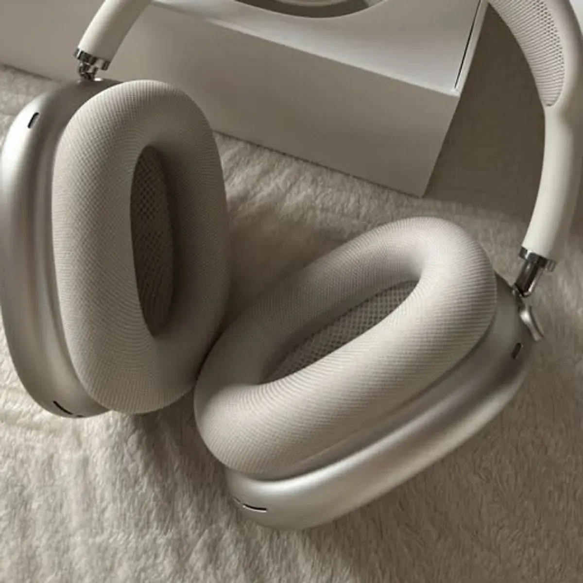 AirPods Max ear cups folded flat showing the Starlight color and mesh texture