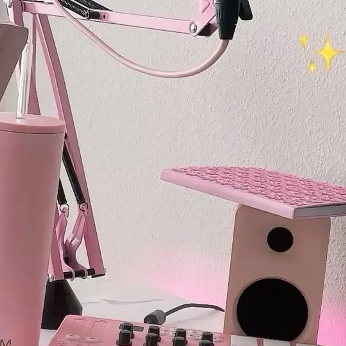 Wider angle of the pink streaming desk with the monitor, speaker and pink LED glow in the background