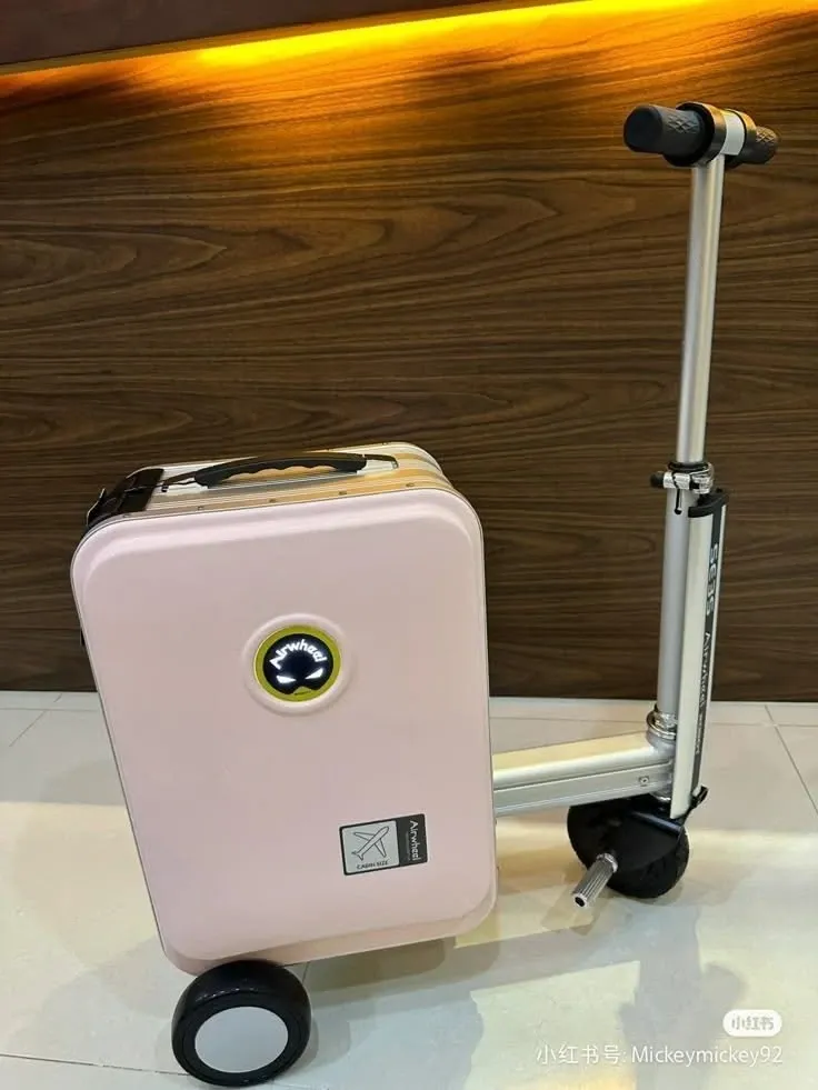 Pink Airwheel SE3S rideable suitcase standing on its wheels next to wooden paneling