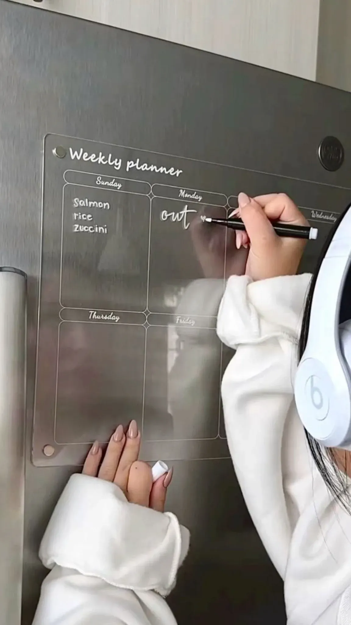 Hand writing the weekly menu on the clear acrylic planner board