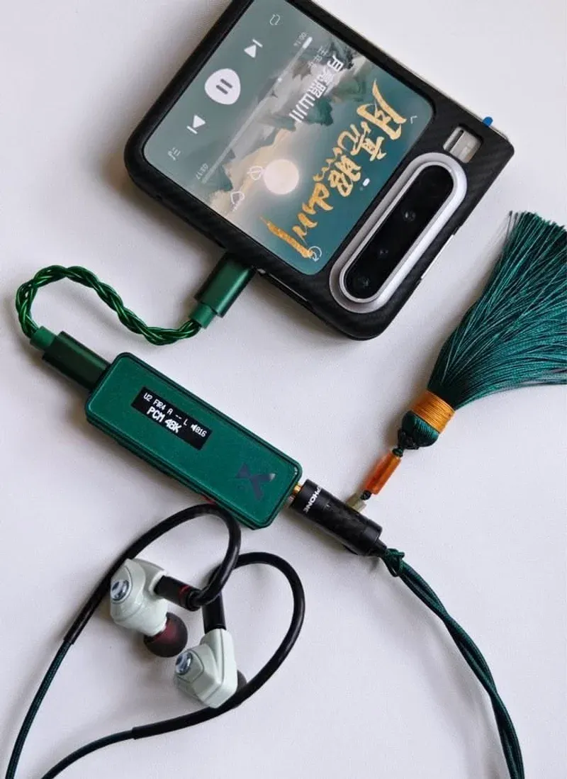 Pocket hi-fi chain with green dongle, phone, and white IEMs